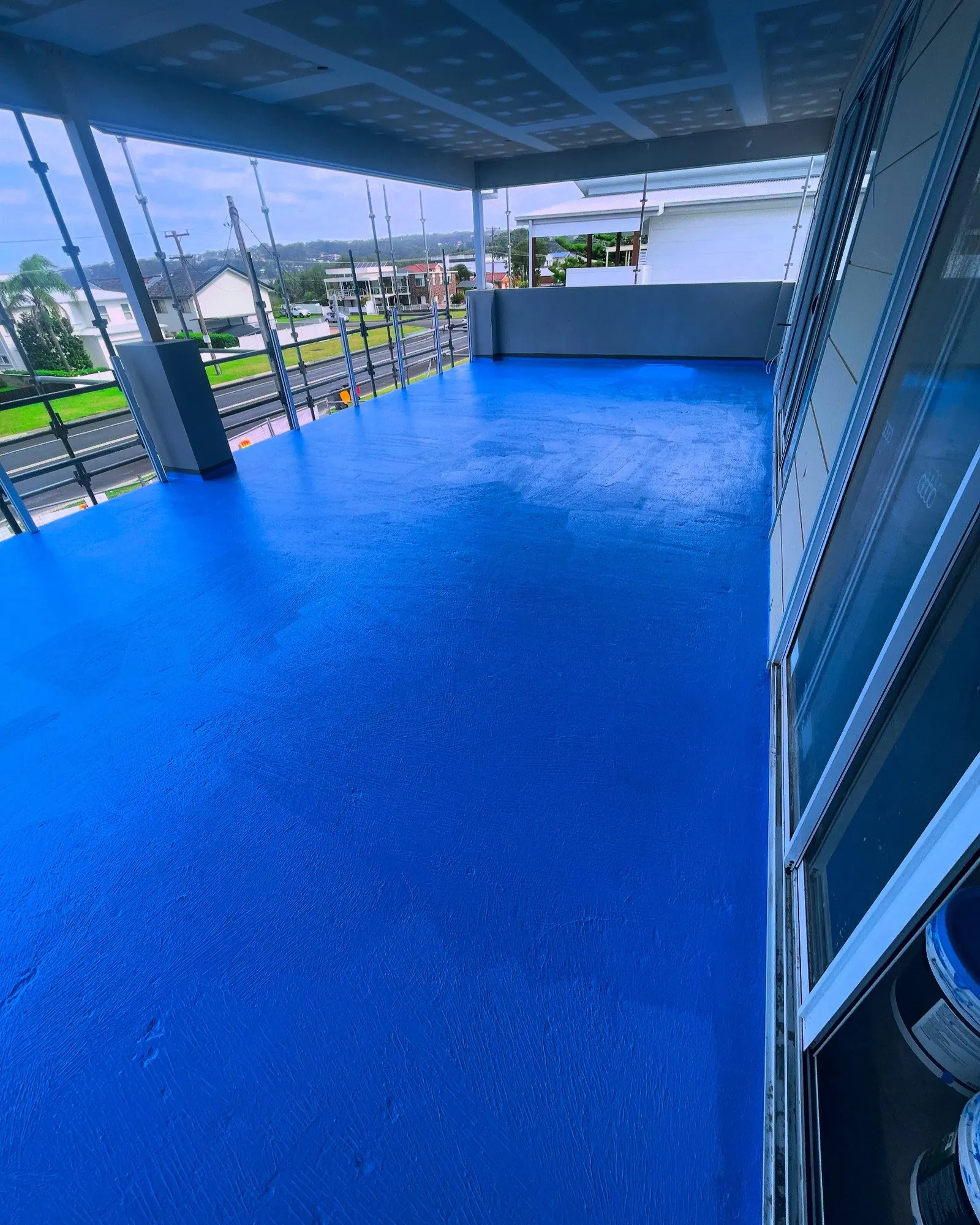 A long covered balcony finished in bright blue membrane, waterproofed by SCW