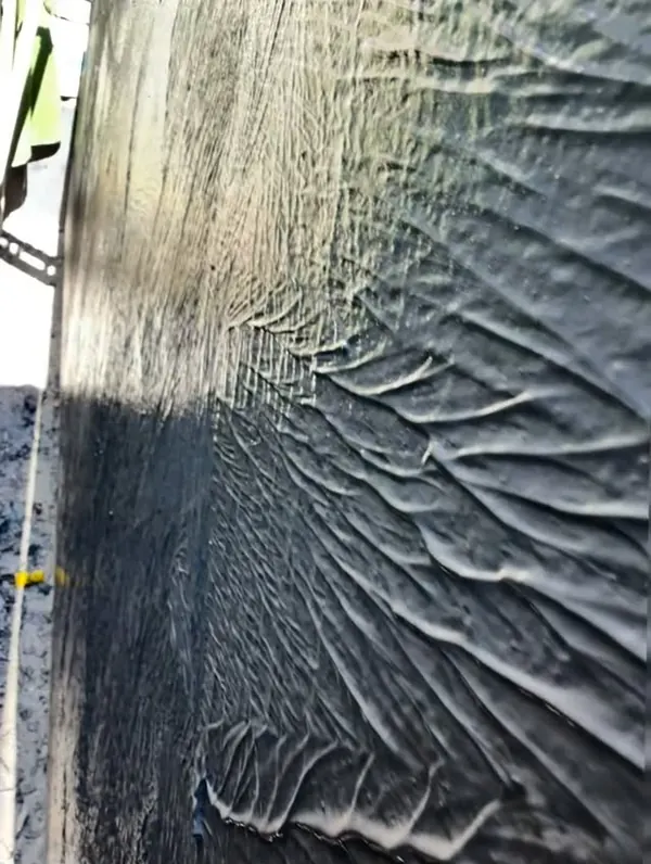 Black membrane on a basement wall below the water table, heavy brush texture
